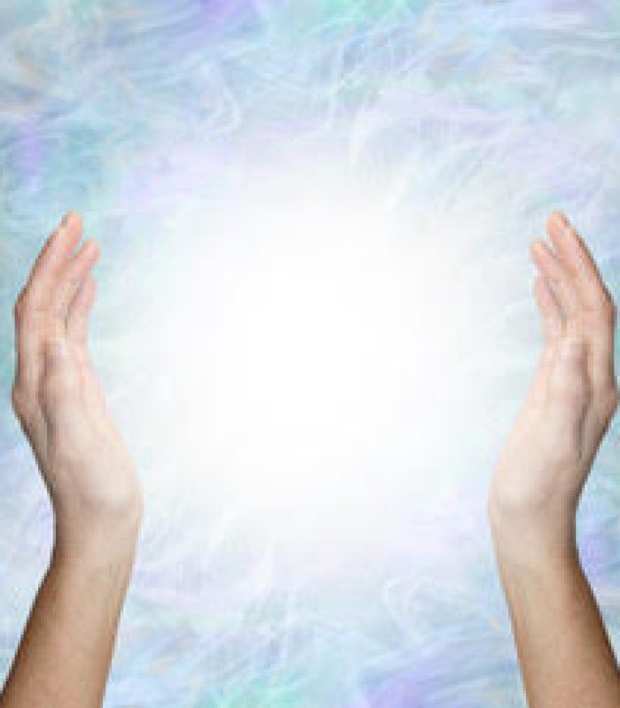 Working with spiritual healing energy - female hands 30cm apart opposite each other with a bright white light orb energy between against a pale blue energy field  background